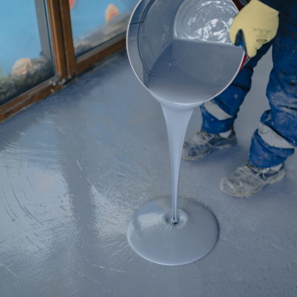 Contractor pouring concrete coating solutions on garage floor job